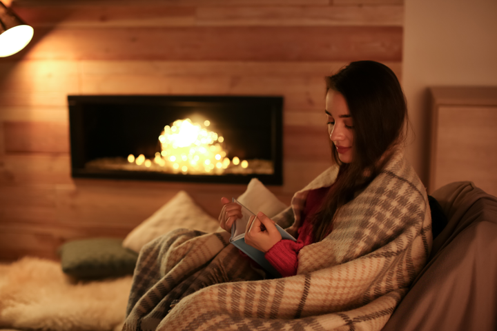 Woman reading book by the fire