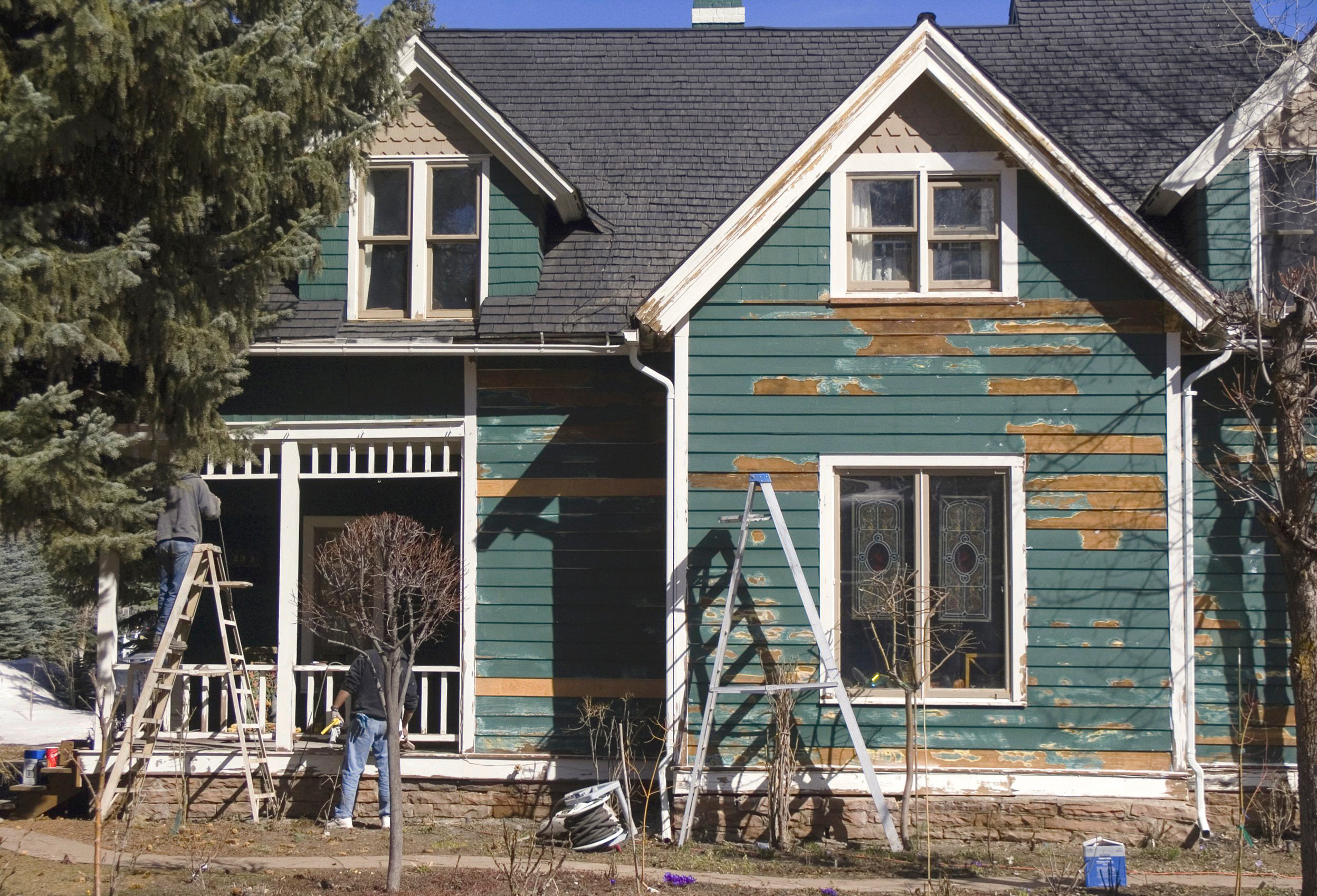 Ladders set up in front of an old, run down house
