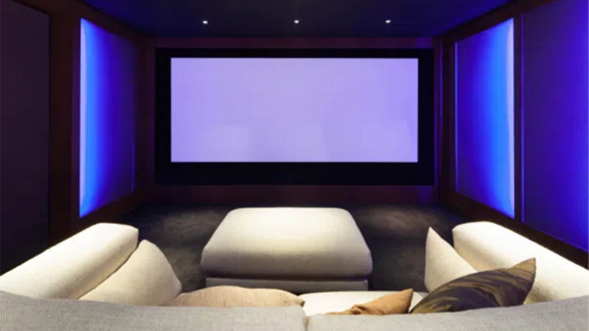 Large couch space faced toward a large projector screen with blue lighting